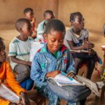 Image of Abel Nelson Manuel, a seven-year-old boy with cerebral palsy, looking at a book in a classroom. Abel received rehabilitation from AMAVIDA, a local partner of Light for the World in Mozambique. In an example of inclusive education, he now attends school and learns with other children his age. Copyright for the photo is Ulrich Eigner / Light for the World