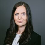 Portraif of Jacqueline Bungart, a woman with dark long hair and blue eyes wearing a black blazer and white shirt